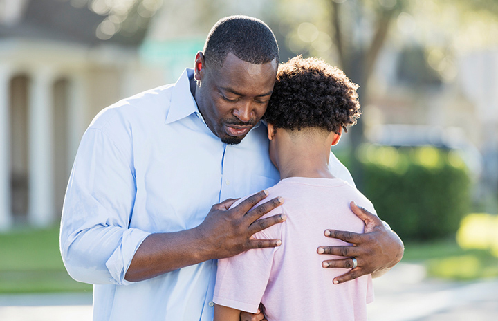 A father and son standing outside hugging eachother.